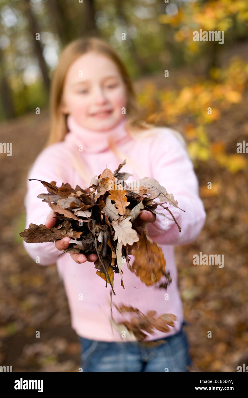 Girl holding autumn leaves in a wood Stock Photo - Alamy