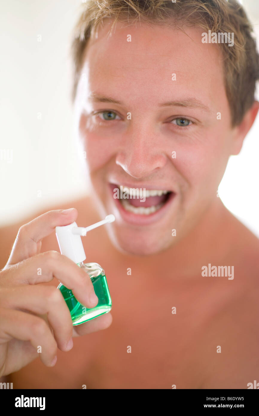 Breath freshener. Man spraying breath freshener into his mouth. This