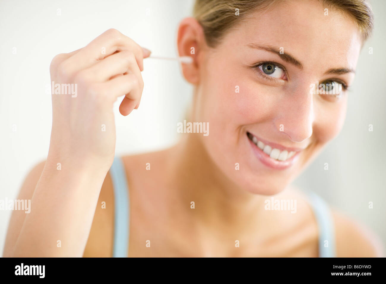 Cleaning ears. Woman using a cotton bud to clean her ear. Cotton buds