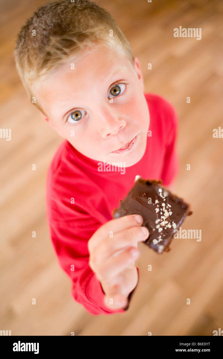 Boy eating chocolate cake. Sweet foods contain high amounts of sugar and fat and eating too much can lead to childhood obesity. Stock Photo