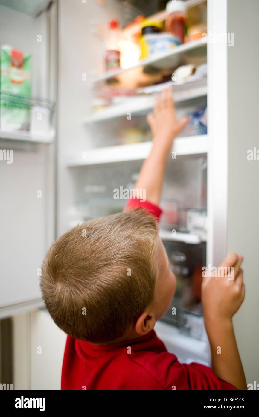 Boy looking in fridge and grabbing an item of food Stock Photo Alamy