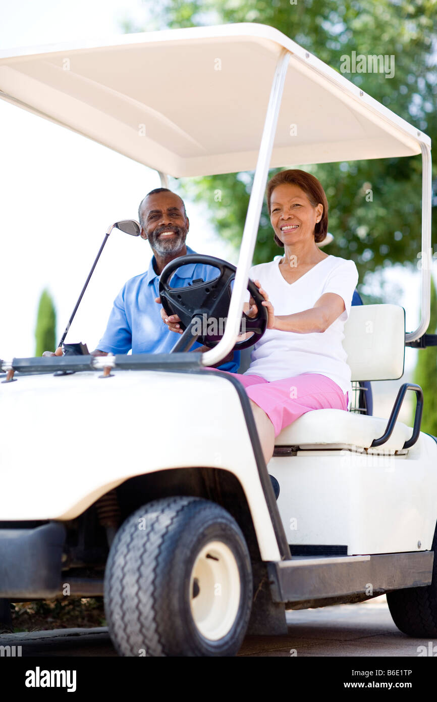 Golf players. Husband and wife using a golf cart during a round of golf. Stock Photo