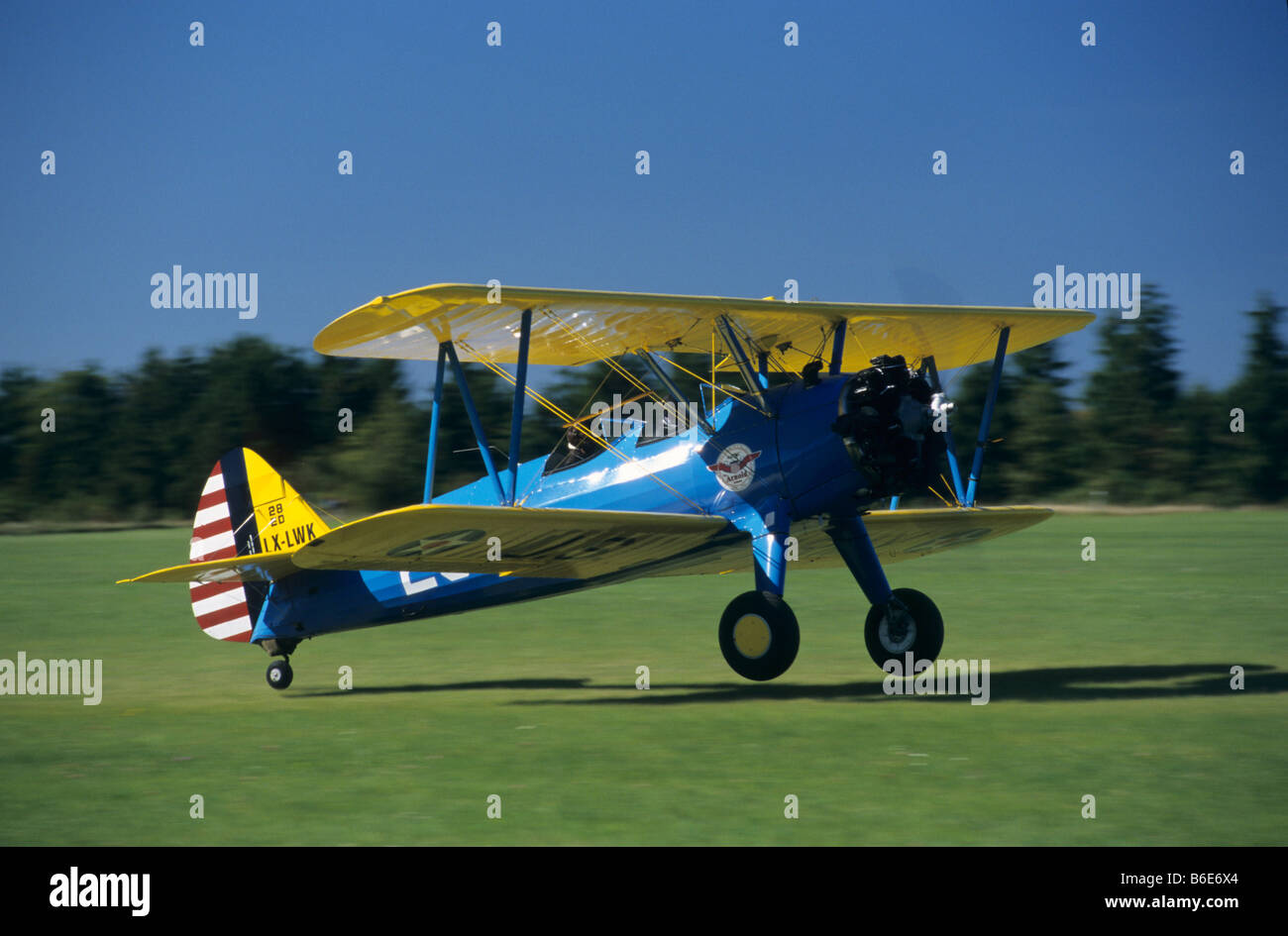 Old american trainer biplane Boeing PT-17 Kaydet / Stearman model 75 landing on a green grass airfield Stock Photo