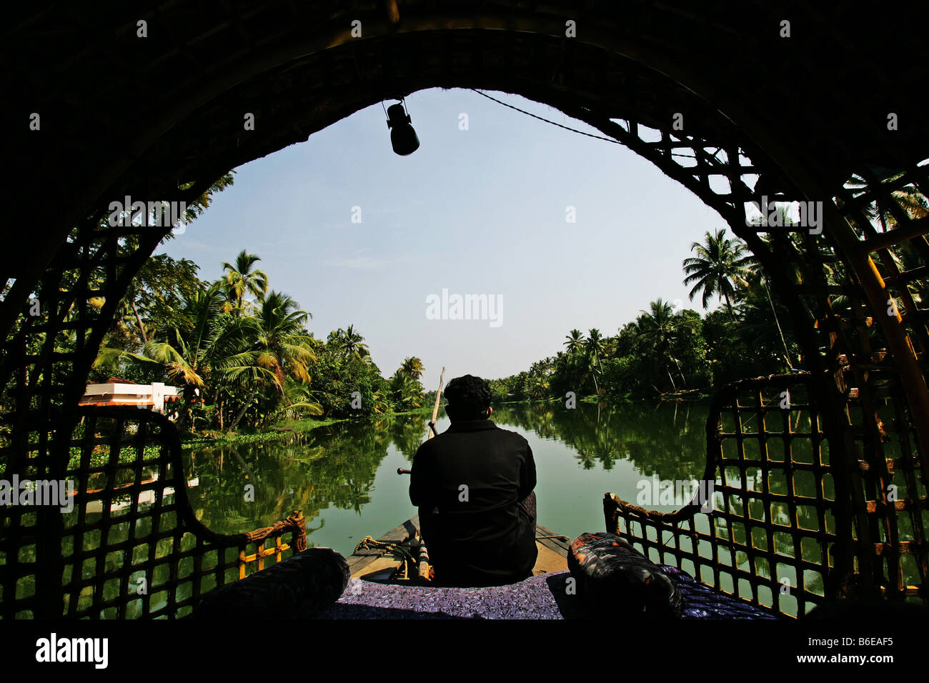A boat captain steers a houseboat along the backwaters of Kerala India Stock Photo