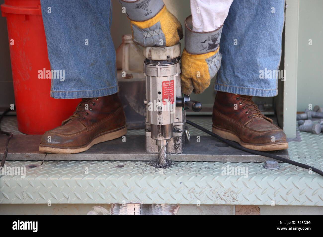An iron worker uses a mag drill to install bolt holes on a bridge floor plate Stock Photo