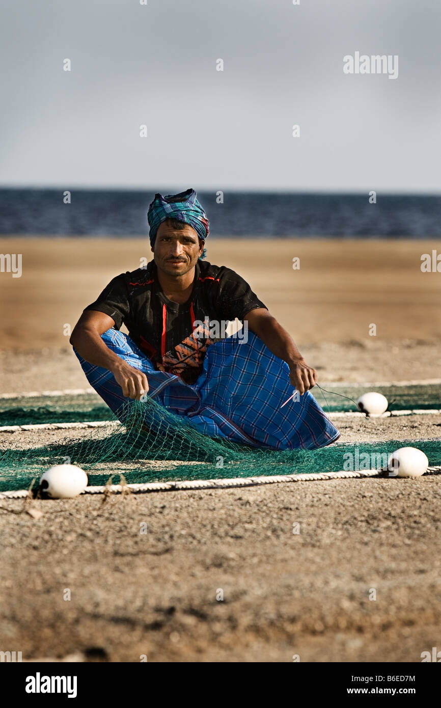Asian Worker Fixing Fishing Nets with Needle Stock Photo