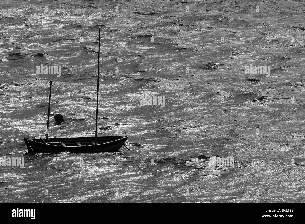 A fishing sail-boat, masts down rocks back and forth on the stormy seas in a strong wind. Solitude, peace, rest and relaxation. Stock Photo