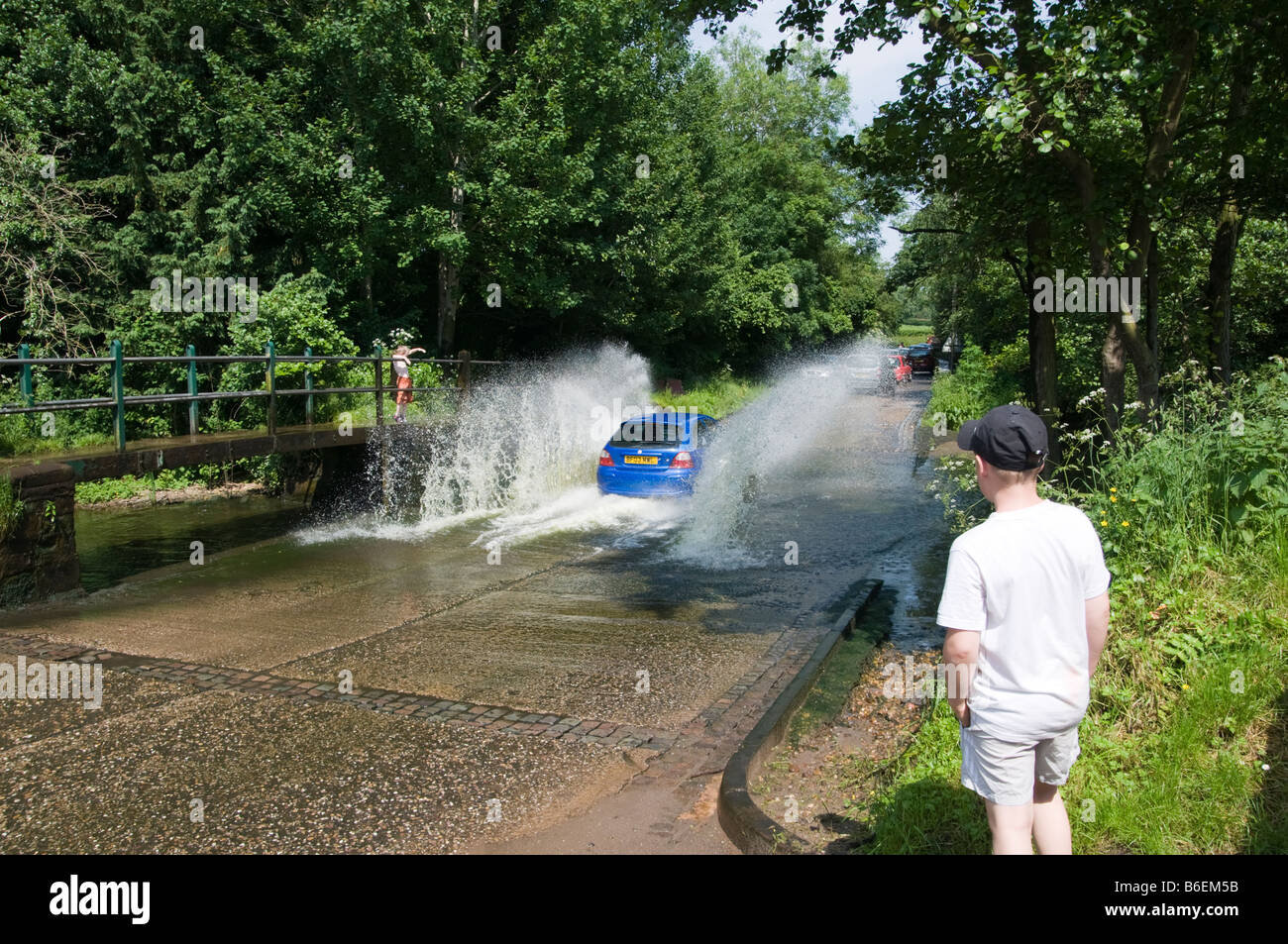 Car going through a ford near Ollerton Nottinghamshire England with young  boy watching Stock Photo
