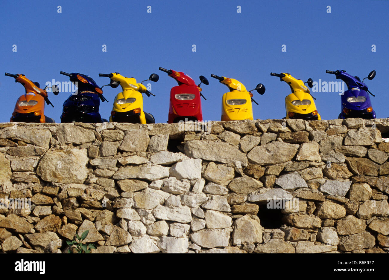 Mopeds lined up by a stone wall, Mykonos city, Mykonos, Greece, Europe Stock Photo