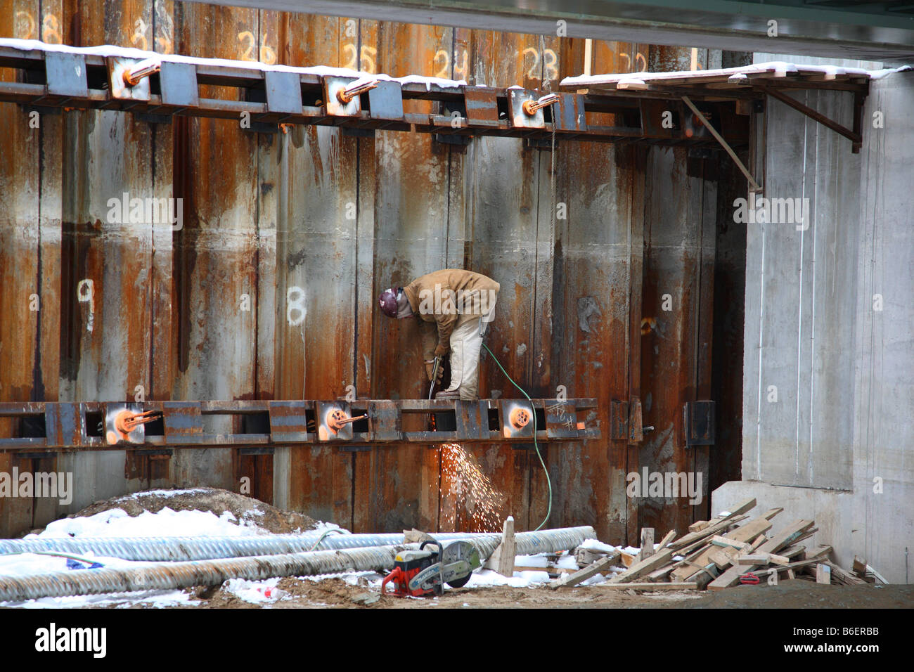 A construction worker torch cuts a waler as part of a temporary tie