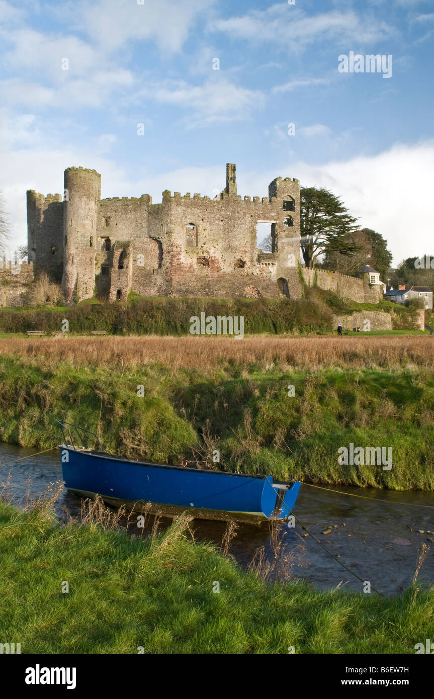Laugharne Castle in Carmarthenshire with blue boat moored in foreground Stock Photo