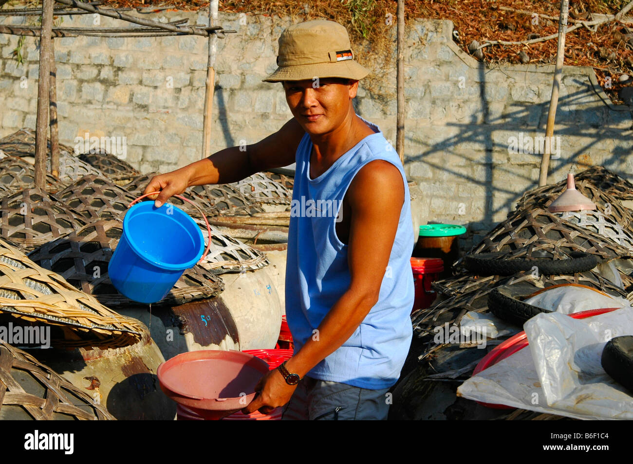 Man decanting the traditional Vietnamese fish sauce Nuoc Mam from an eartenware amphora, Mui Ne, Vietnam, Asia Stock Photo