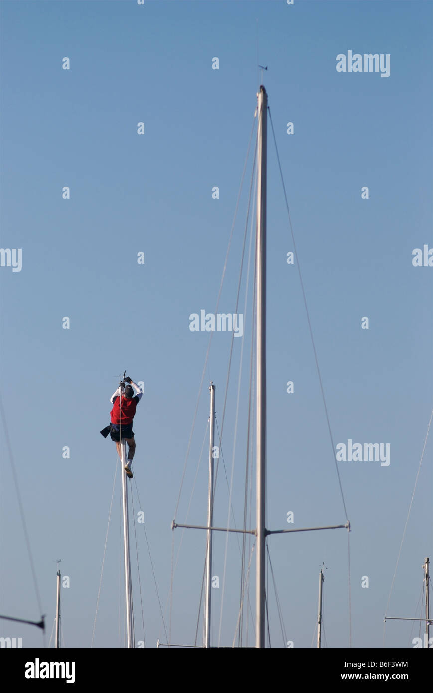 Sailor going aloft at the harbor to repair wind sensors at the mast top. f Stock Photo