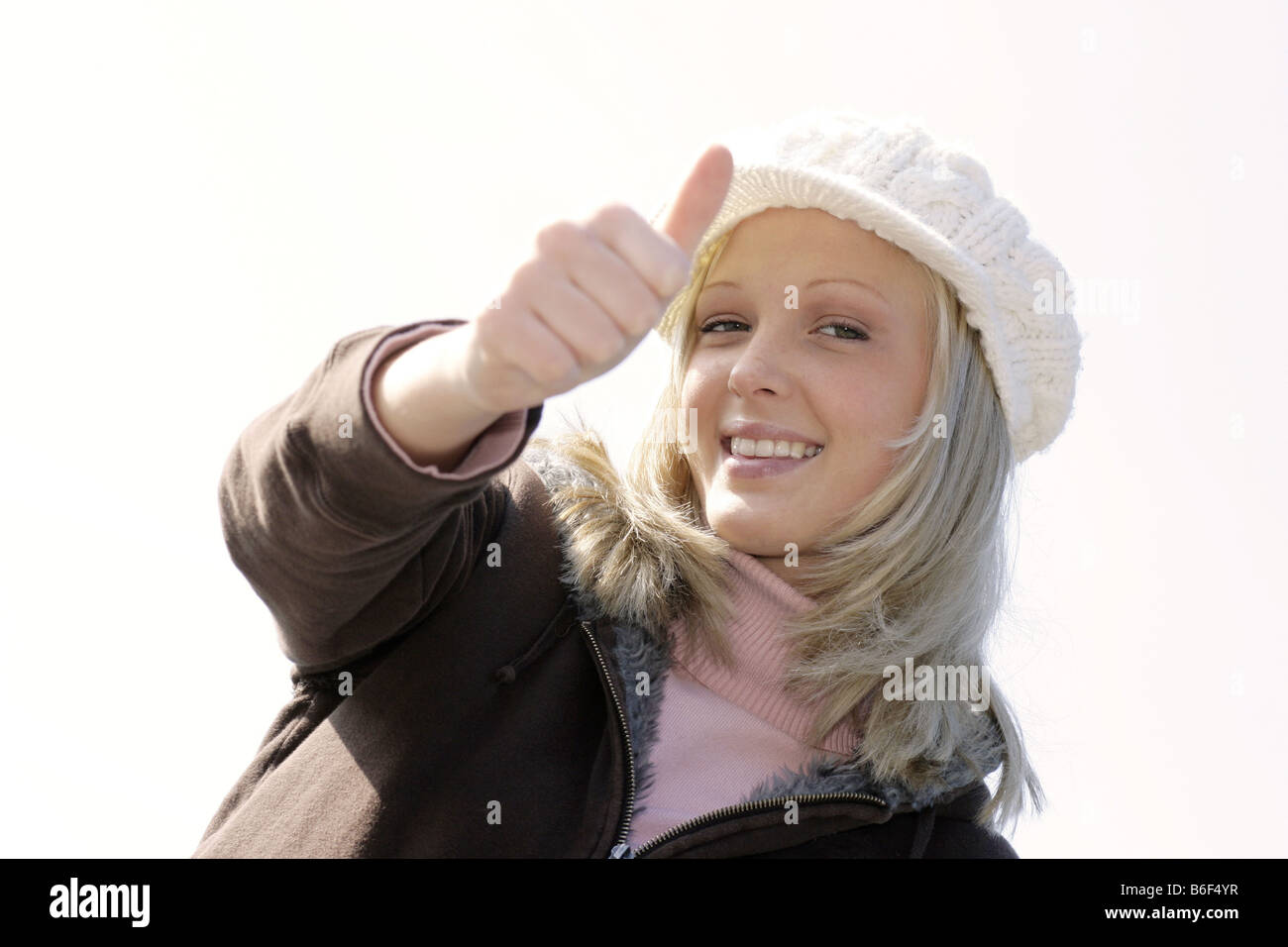 young blond woman with cap makes thumb up Stock Photo