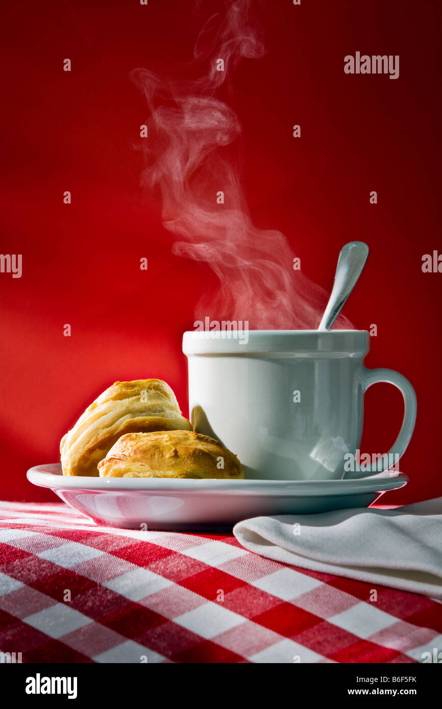 hot steaming coffee or tea with biscuits or scones in morning sunlight Stock Photo