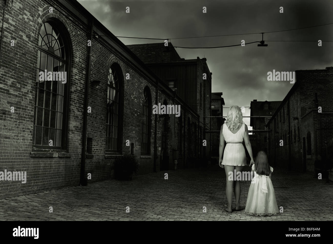 Woman and a child in a dark empty street Stock Photo