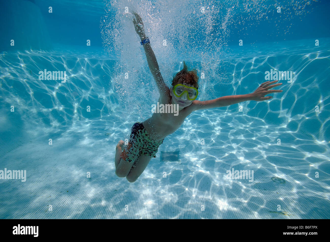 6yearold boy wearing diving goggles, diving in a swimming pool
