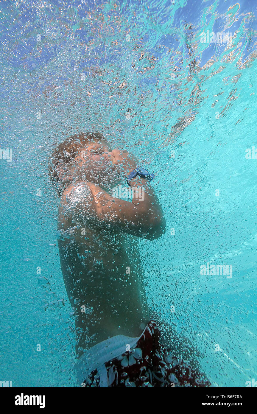 6yearold boy in water holding his nose surrounded by air bubbles