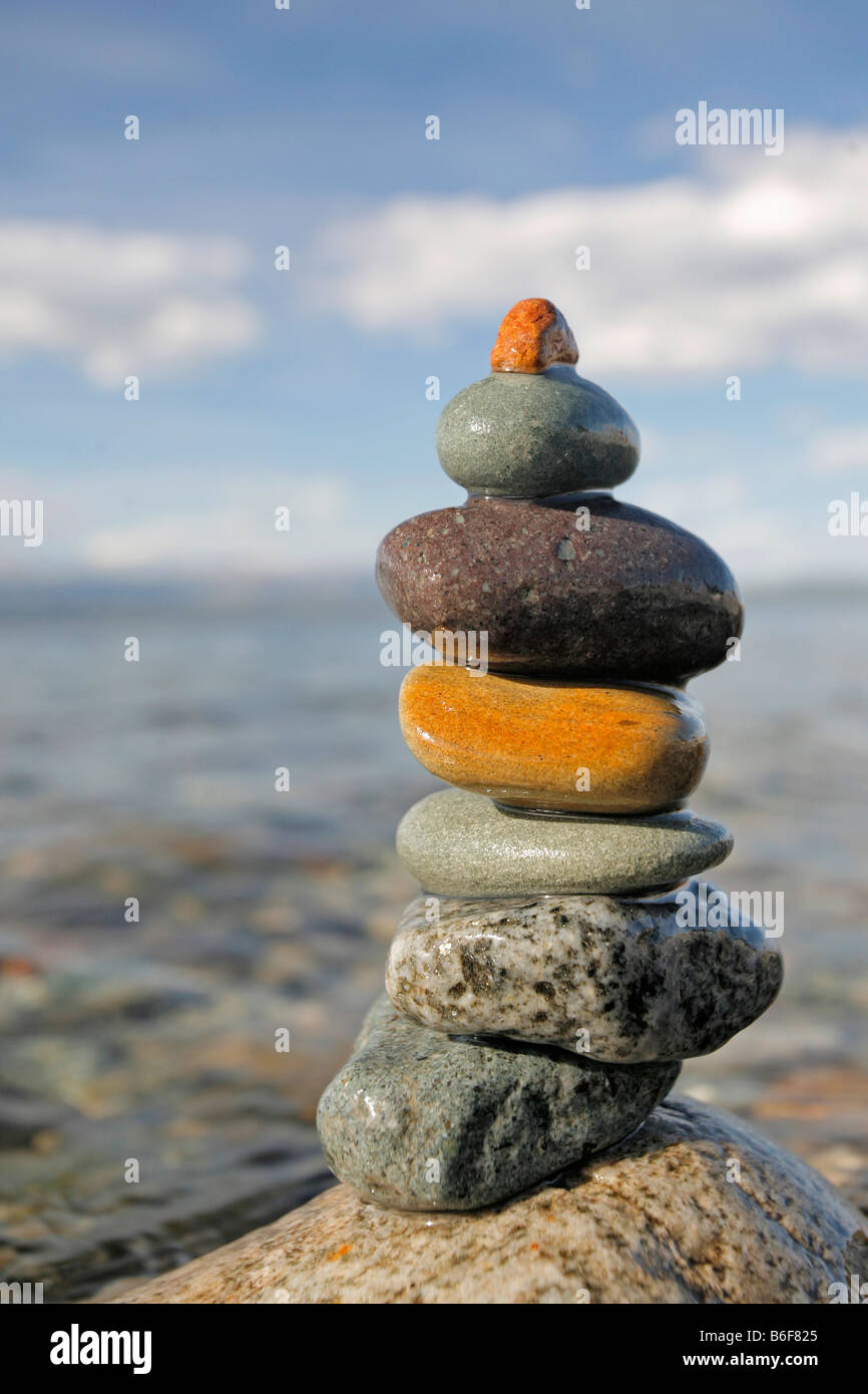 Stack of multicolored volcanic pebbles by calm water Stock Photo