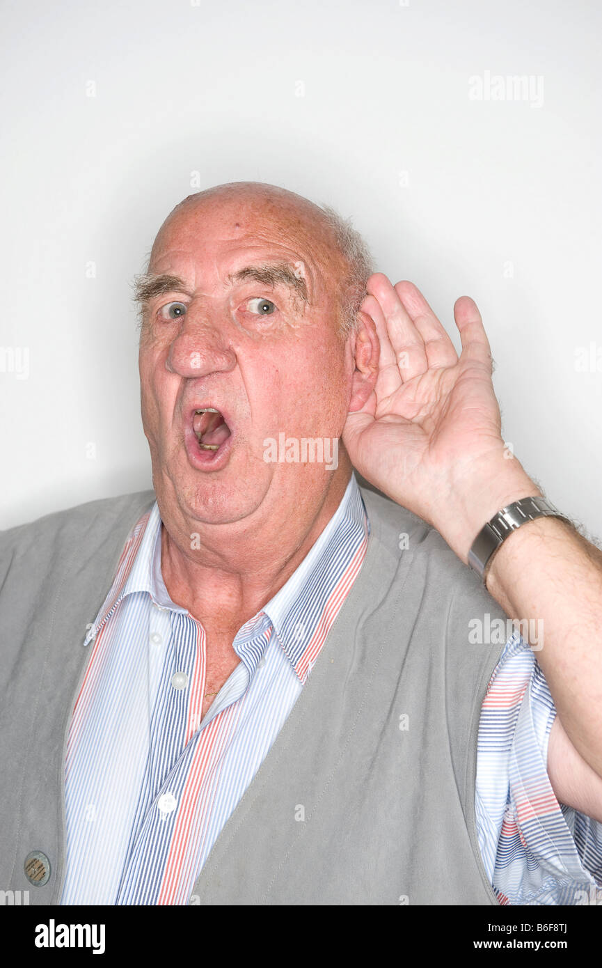 Elderly man acting, his hand at his ear Stock Photo