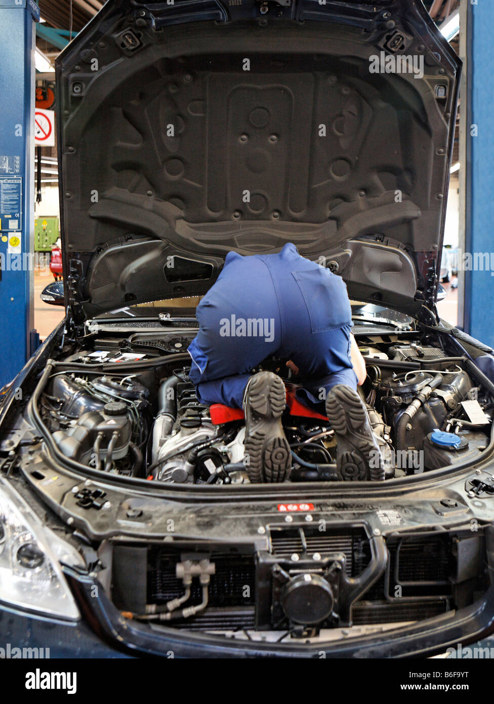 Mechanic Kneeling On The Engine Block Of A S Class Mercedes In The Stock Photo Alamy