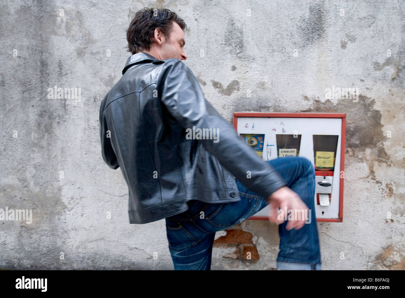 Young man kicks a chewing gum vending machine Stock Photo