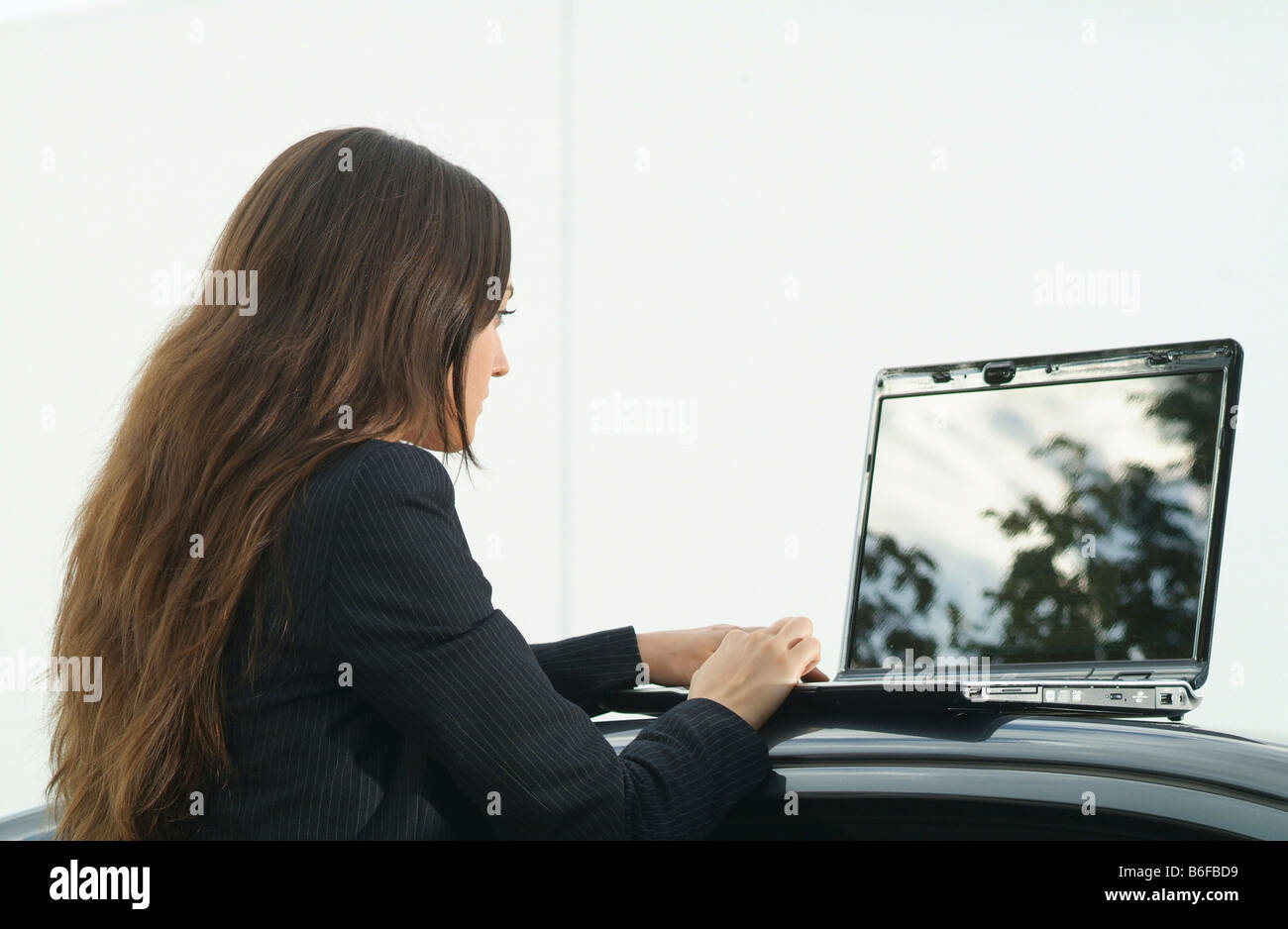 Young businesswoman with a laptop on the roof of the car Stock Photo