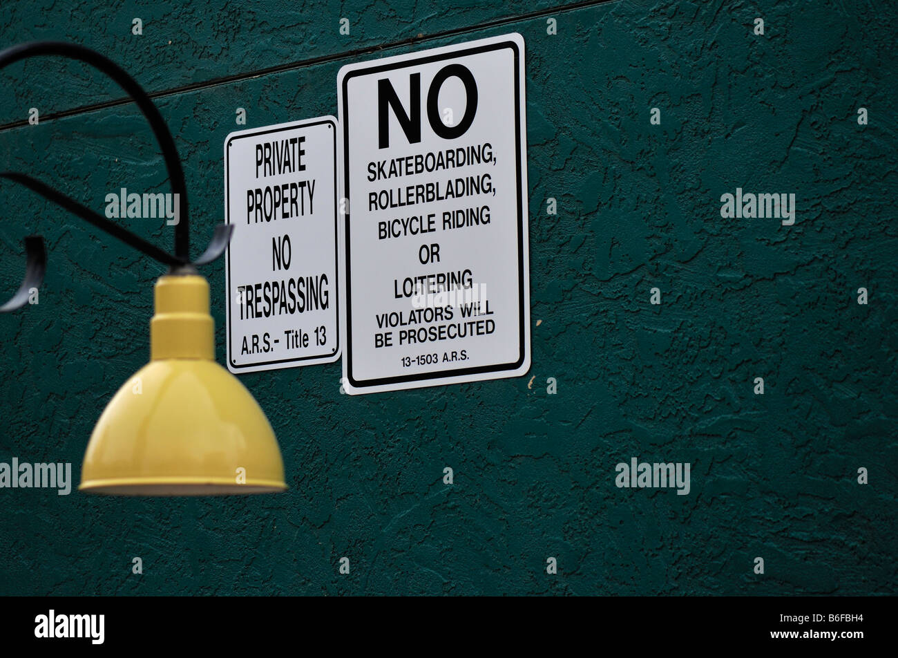 Prohibitive signs on a green wall next to a friendly yellow lamp Stock Photo