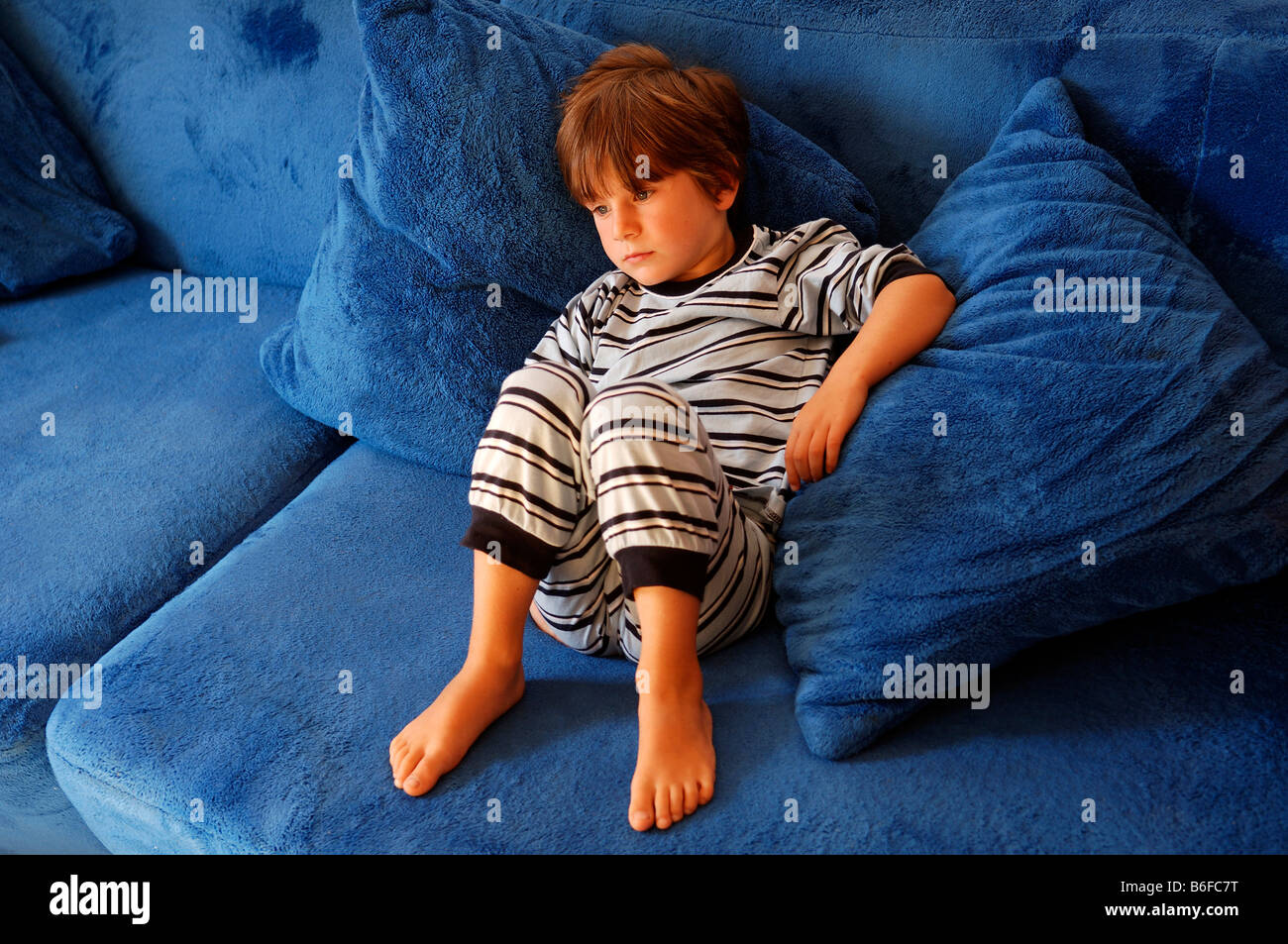Young boy sitting on a blue sofa watching television, in Illhaeusern, Alsace, France, Europe Stock Photo