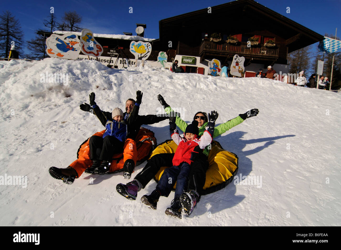 Family snow tubing in front of the Rotwandwiesenhuette or Pietrarossa