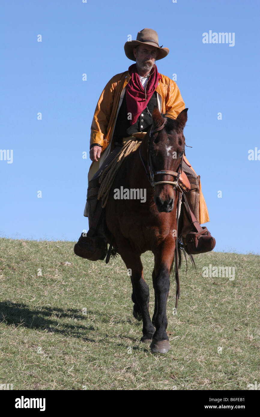 A cowboy riding his horse down a hill in Texas Stock Photo