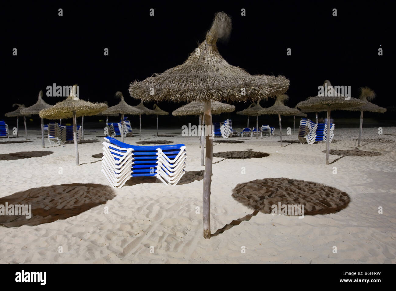 Sunshades and stacked deckchairs on the beach of Sa Coma at night, Majorca, Balearic Islands, Spain, Europe Stock Photo
