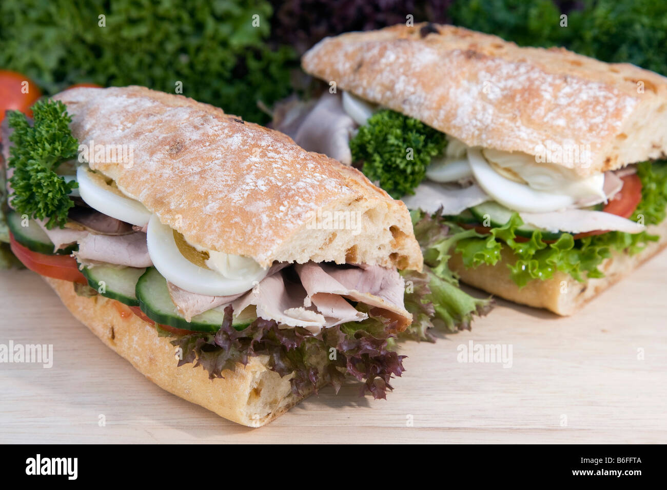 Onion baguette with salad, tomatoes, cucumber, roast pork, egg and mayonnaise Stock Photo