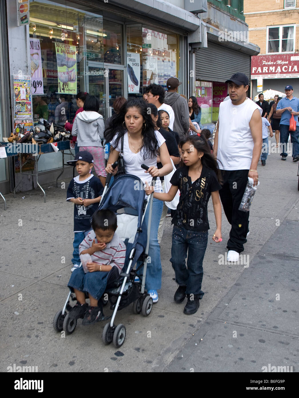 Hispanic woman with three children walks on 5th Avenue the main shopping street in Sunset Park Brooklyn New York Stock Photo