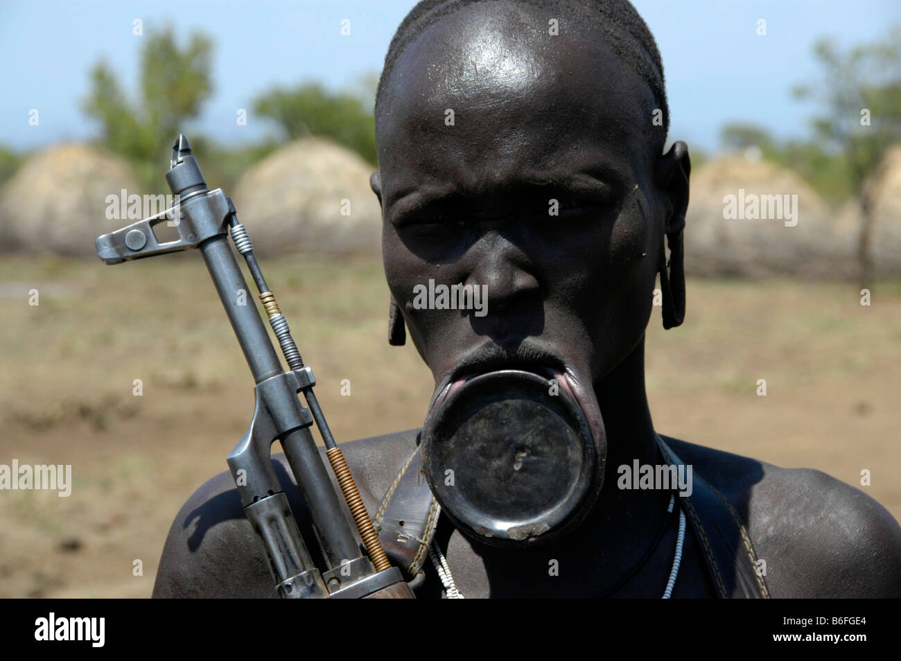 Woman with plate lip and a machine gun, Kalashnikov, from the Mursi tribe, Jinka, Ethiopia, Africa Stock Photo