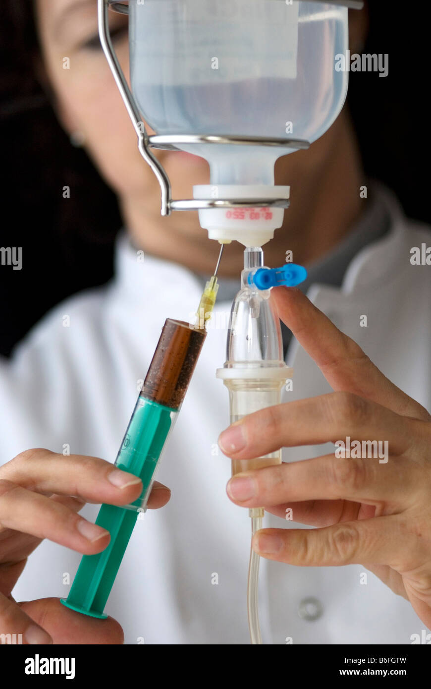 Doctor preparing an infusion by injecting medicine into the infusion ...