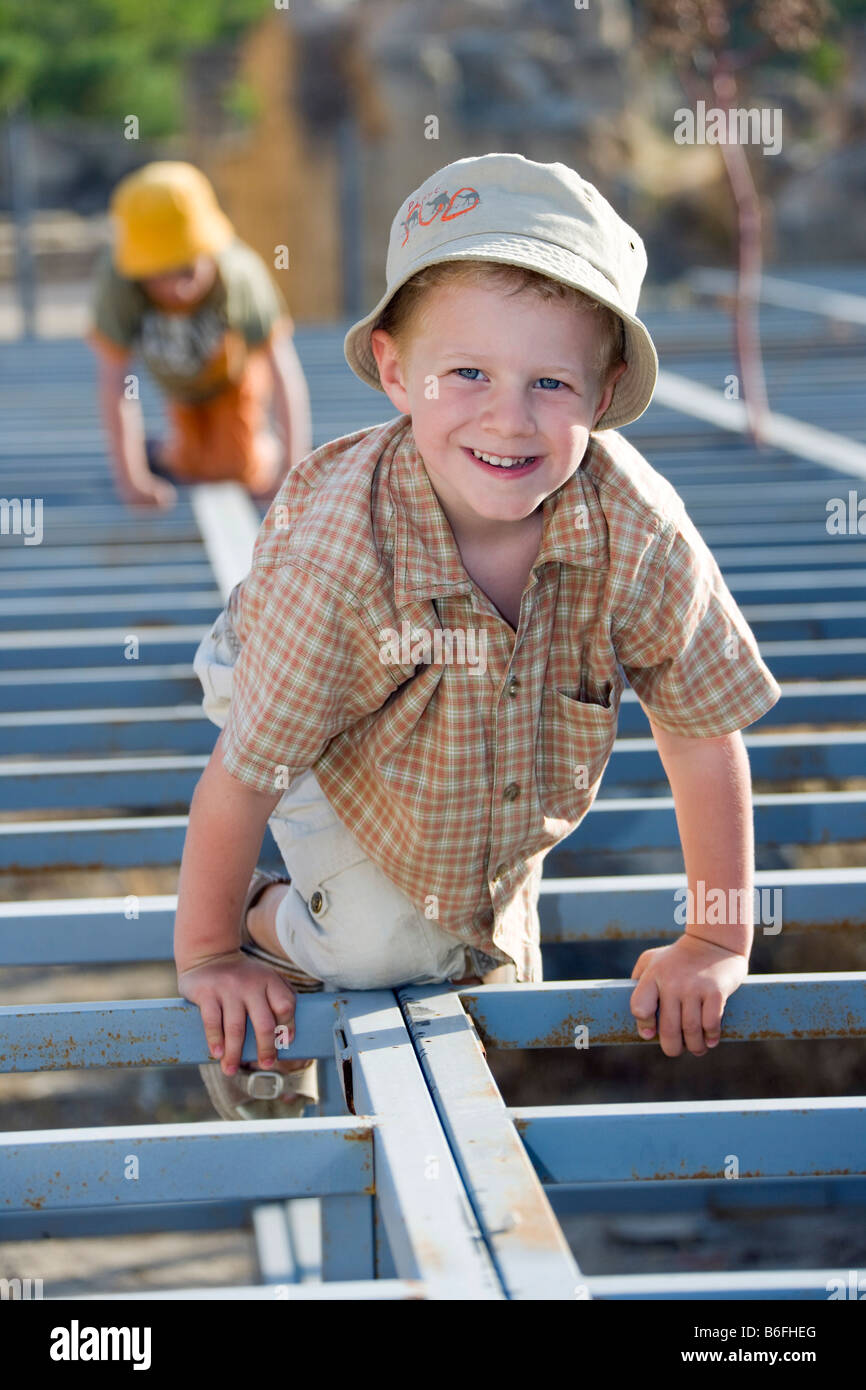 Two boys climbing on a long steel framework Stock Photo