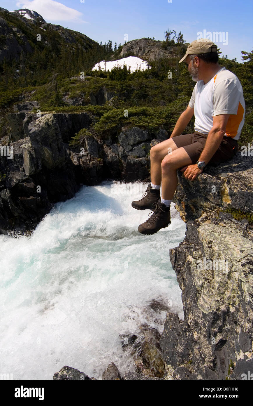 Hiker sitting, resting over water fall, Chilkoot Trail, Chilkoot Pass, British Columbia, B.C., Canada, North America Stock Photo