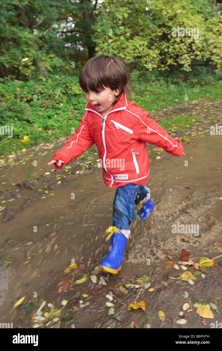 Child wearing rubber boots walking through puddles, Niederwerth, Rhineland-Palatinate, Germany, Europe Stock Photo