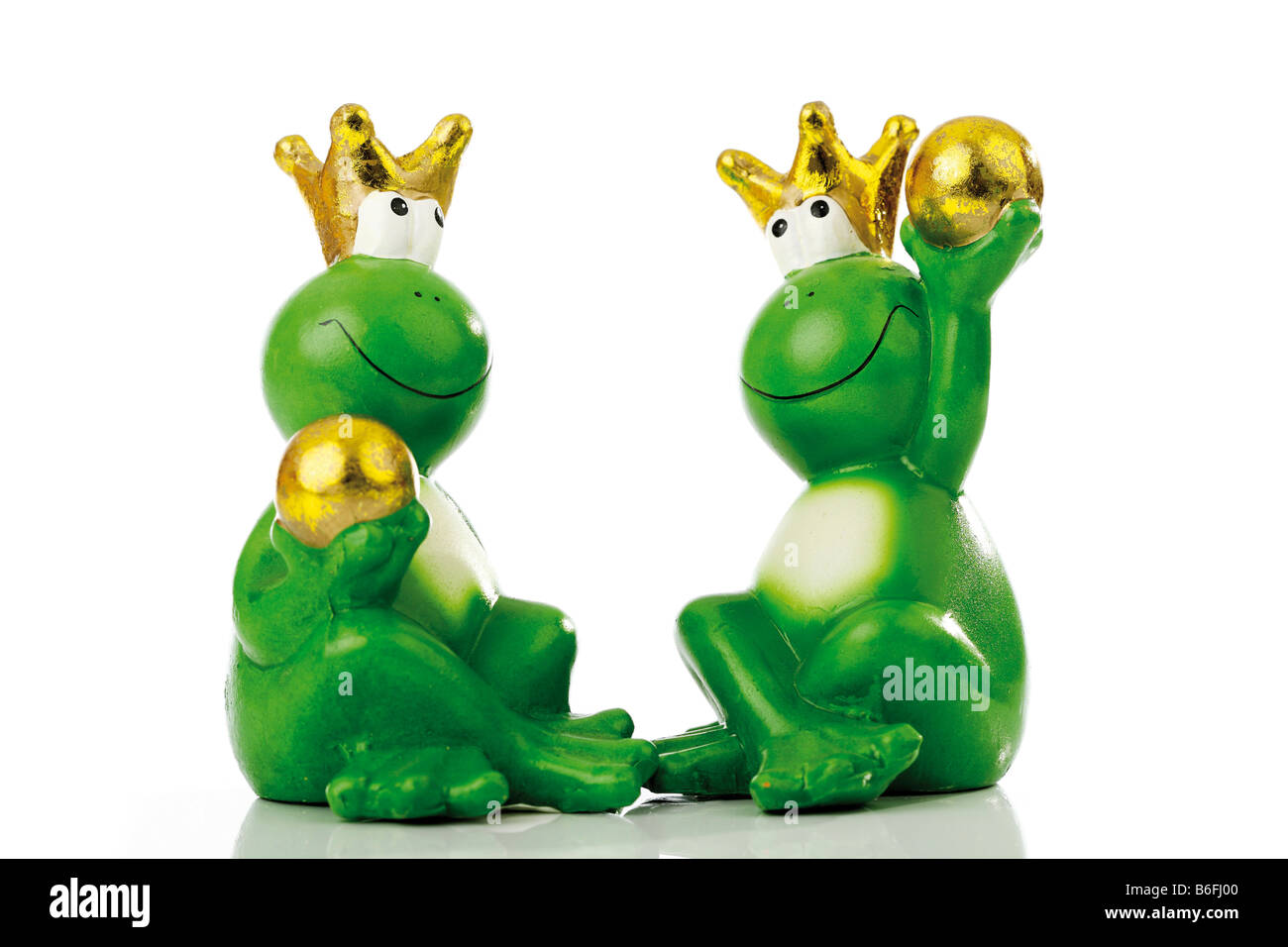 Frog princes or kings each holding a golden ball Stock Photo