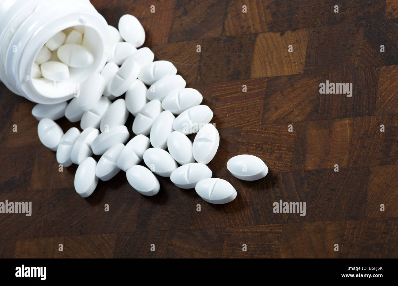 Pills from a glass shown on wood Stock Photo
