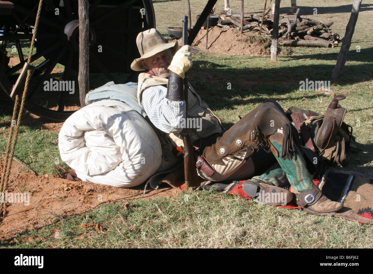 A seasoned cowboy resting against his bedroll next to the chuck wagon in camp Stock Photo