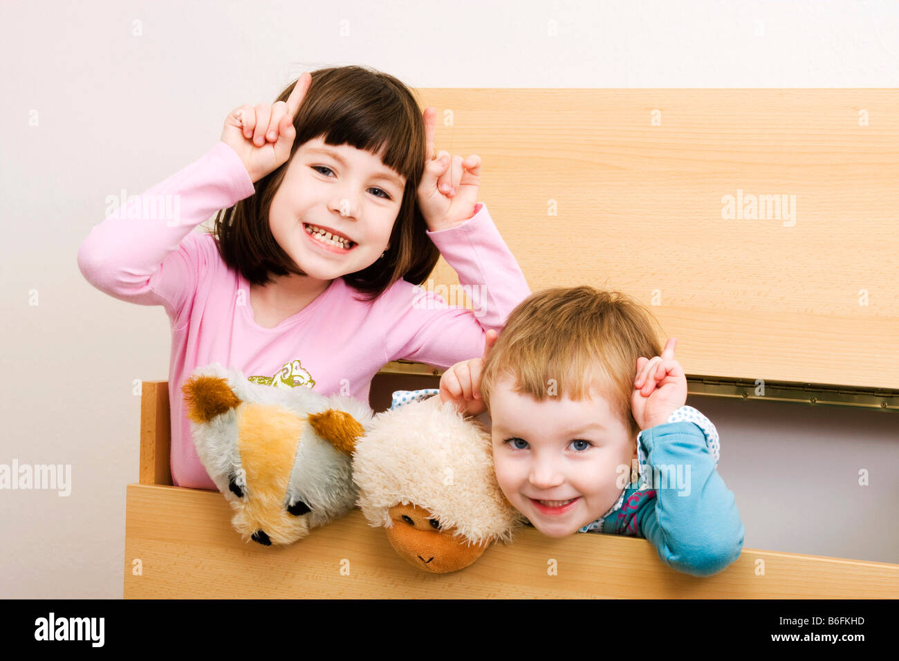 Two sisters, 6 and 3 years old, with dog-ears, brunette and blonde, indoors Stock Photo
