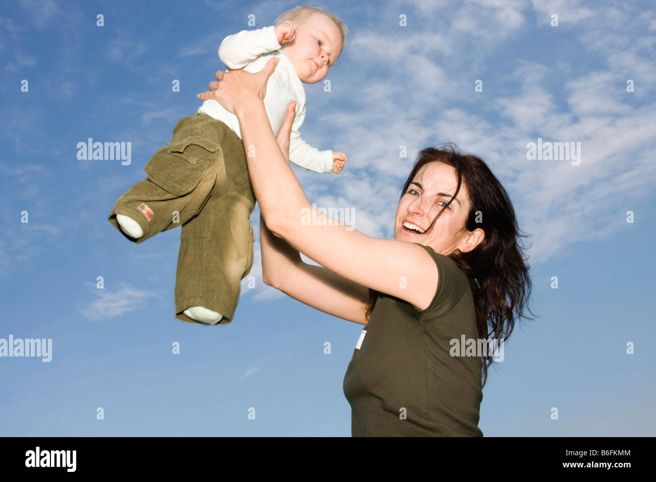 Happy mother, 32 years, holding her baby girl, 9 months, outside Stock Photo