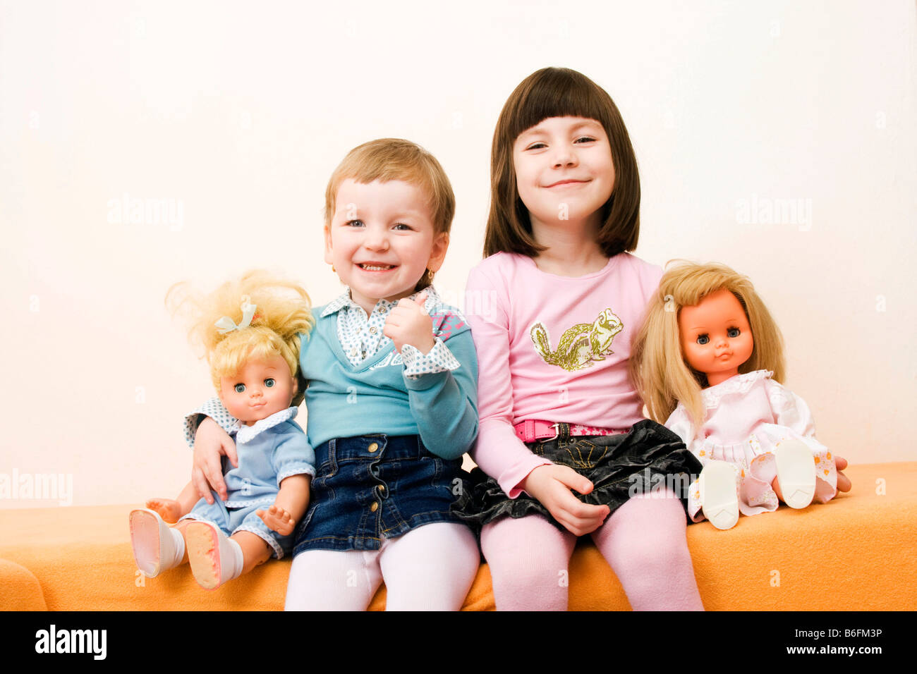 Little girls, 3 and 6 years, with dollies, indoors Stock Photo