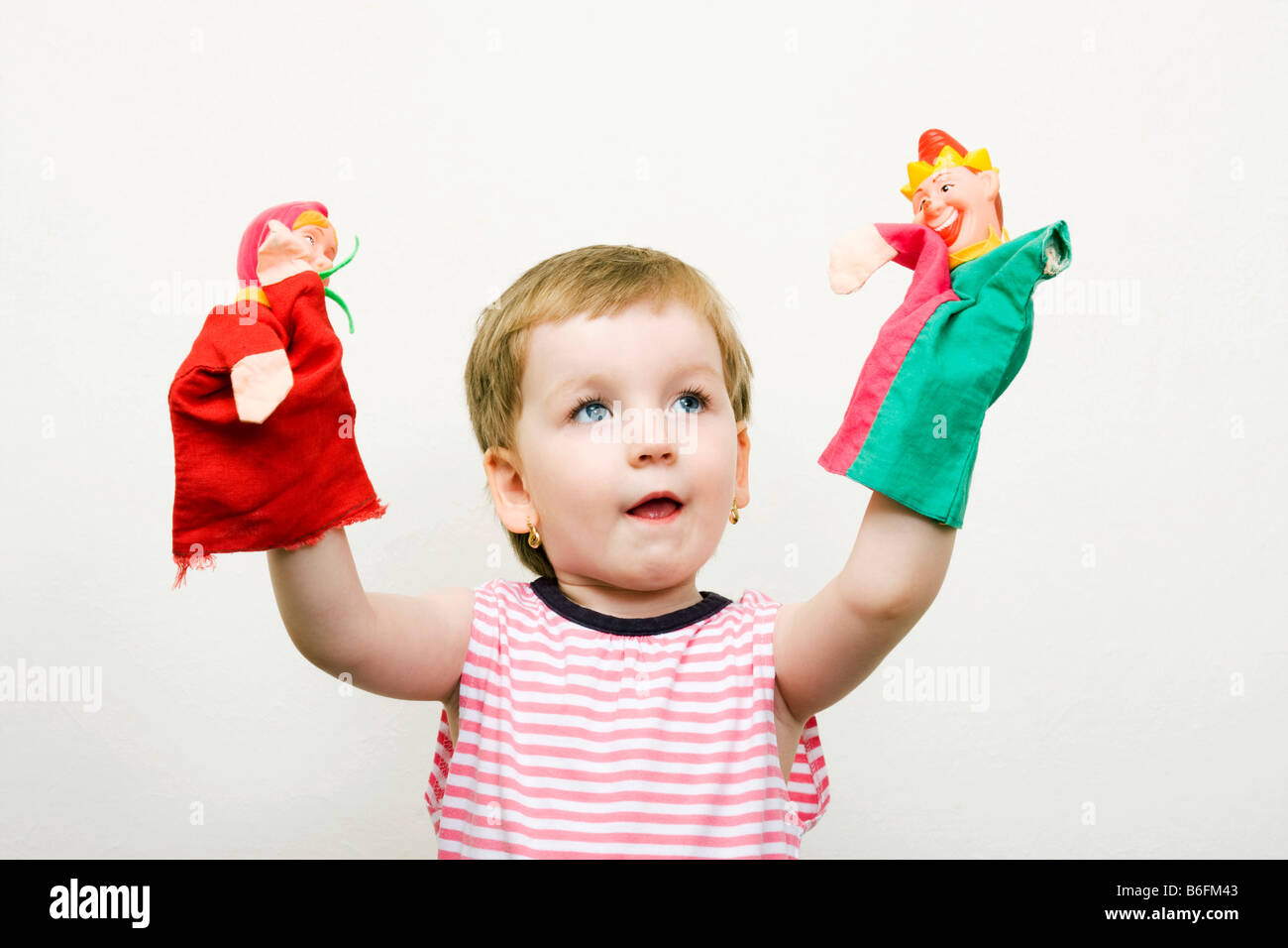 Little girl, 3 years, with two puppets Stock Photo