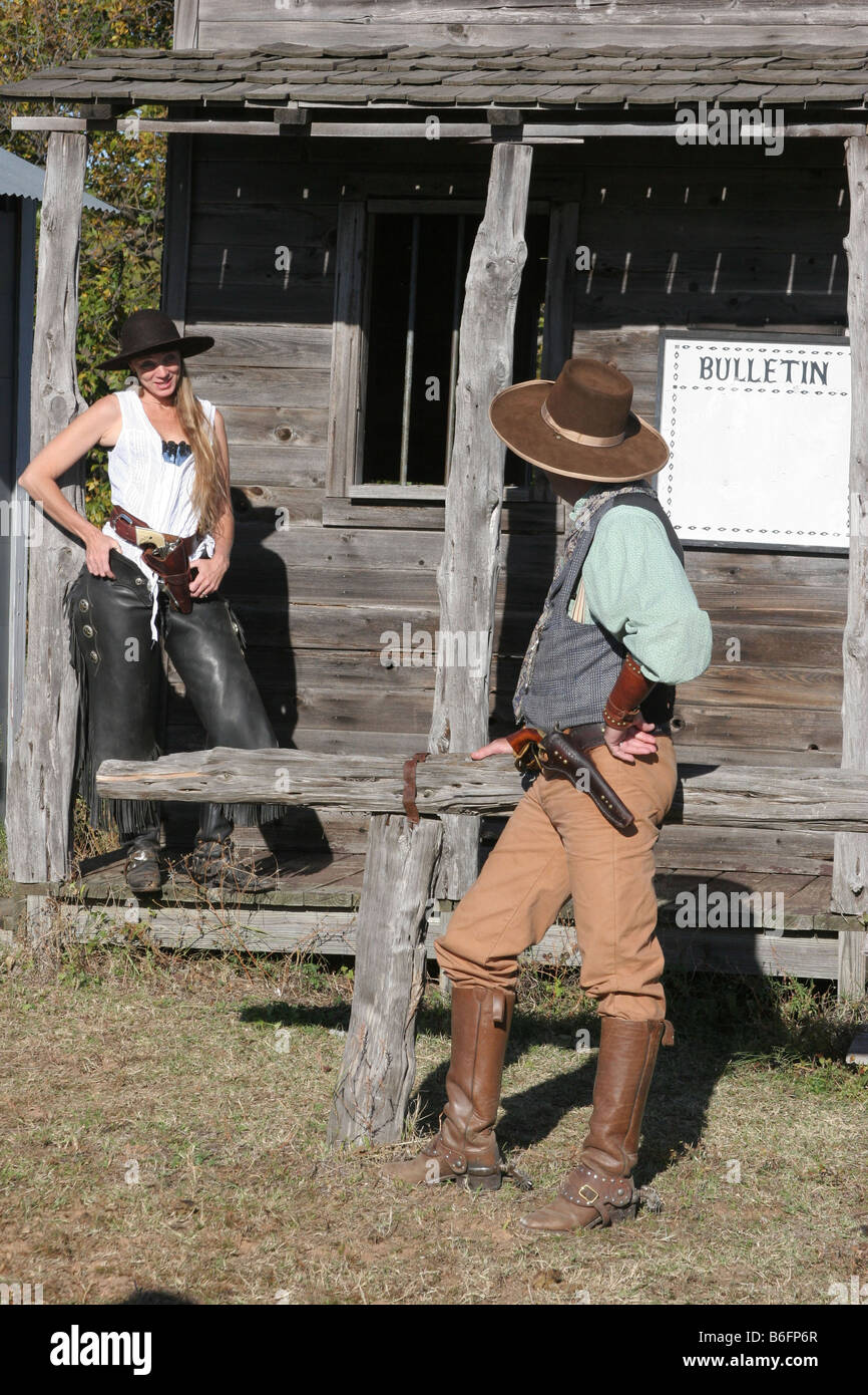 A cowboy talking to a young lady cowgirl standing on the boardwalk of an old western town Stock Photo