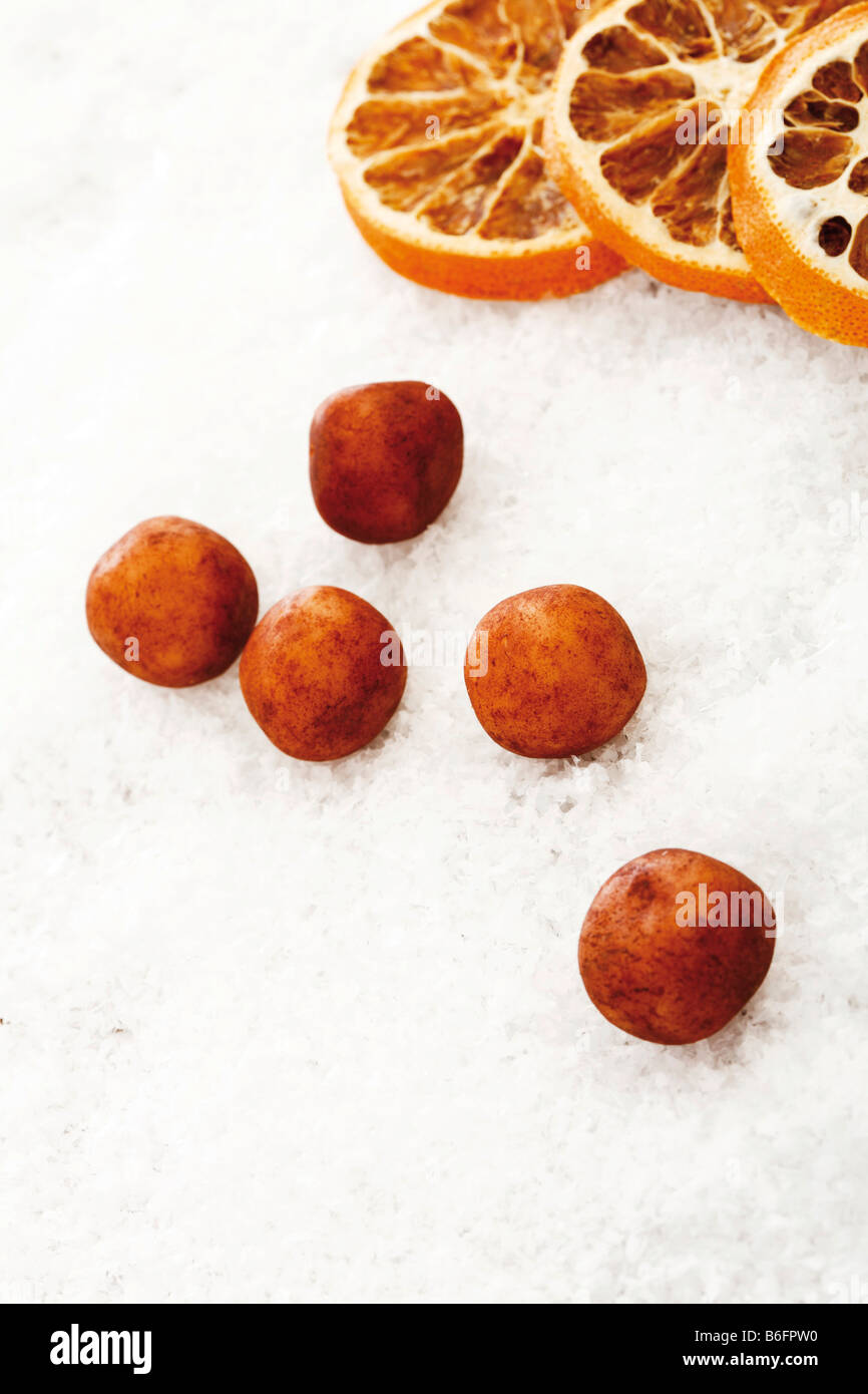 Marzipankartoffeln, Marzipan Balls, and dried orange slices on snow Stock Photo
