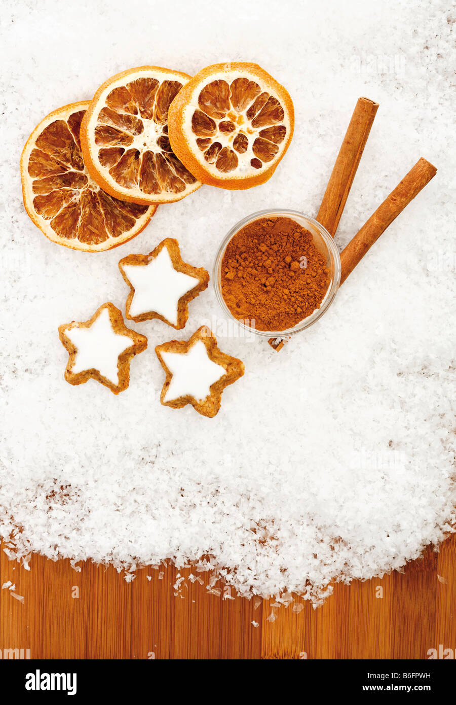 Cinnamon Stars with dried orange slices and cinnamon sticks on snow Stock Photo