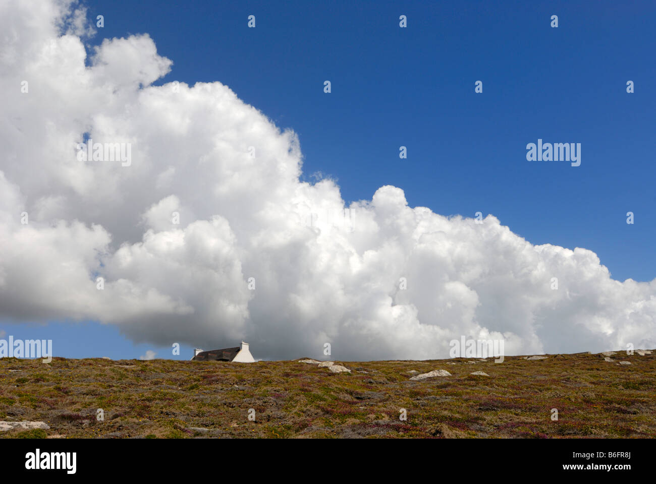 Band of clouds in a blue sky over a lone house in Brittany, France, Europe Stock Photo
